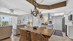 A modern kitchen with a wooden dining table, wicker chairs, and a chandelier.