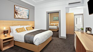 Una habitación de hotel con una cama grande, mesitas de noche, un escritorio y un televisor.