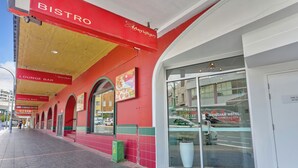 Entrada de un hotel con puerta de cristal, letrero del Hotel Meridian y señal de seguridad contra incendios visible.
