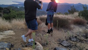 Une personne prend une photo d’une autre personne, avec un magnifique coucher de soleil en arrière-plan.