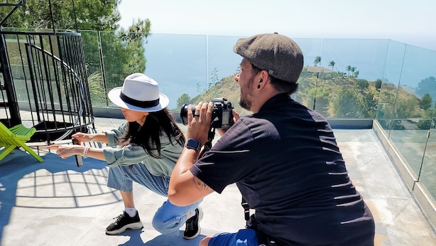 Une personne prend une photo d’une autre personne sur un balcon offrant une vue panoramique.