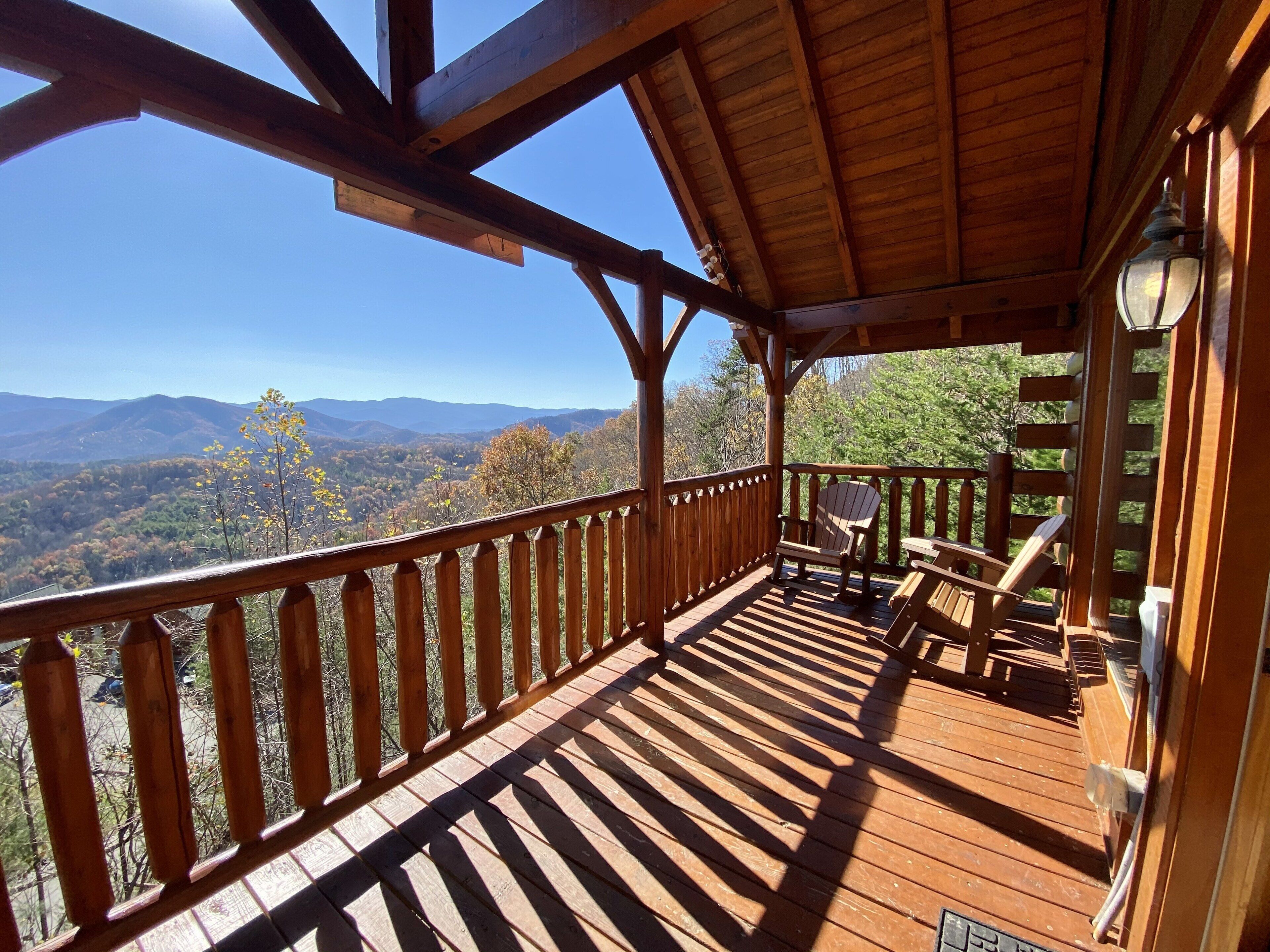 A wooden deck with a view of mountains and trees.