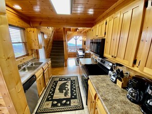 Une cuisine rustique, située dans une cabane en bois, avec un îlot central, des comptoirs en granit et un four à micro-ondes.