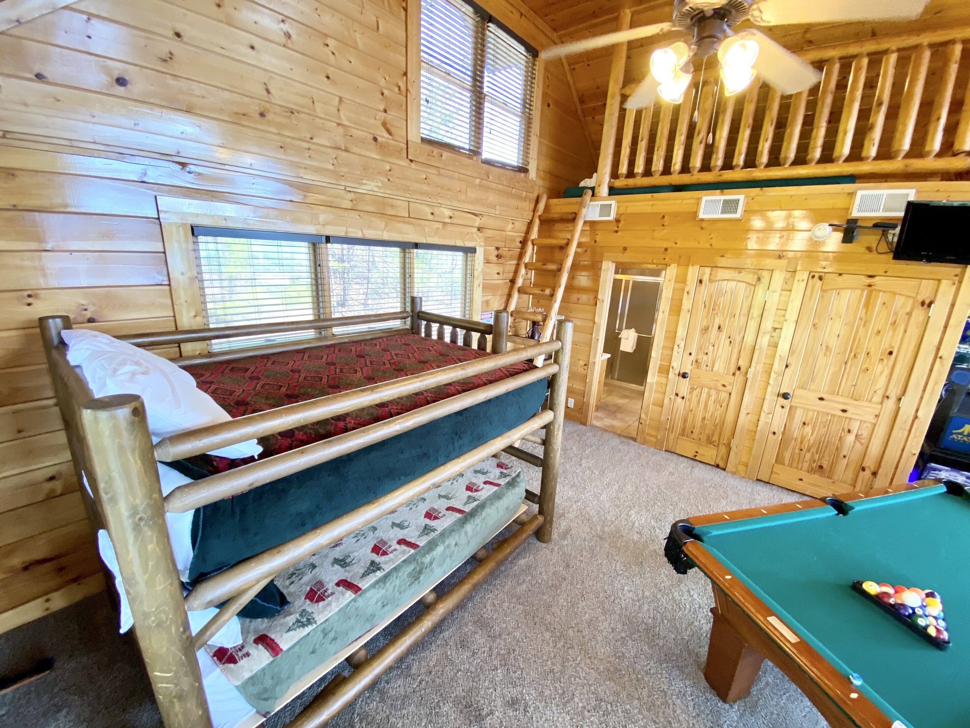 Eine Holzhütte mit Etagenbett, Billardtisch und Deckenventilator.