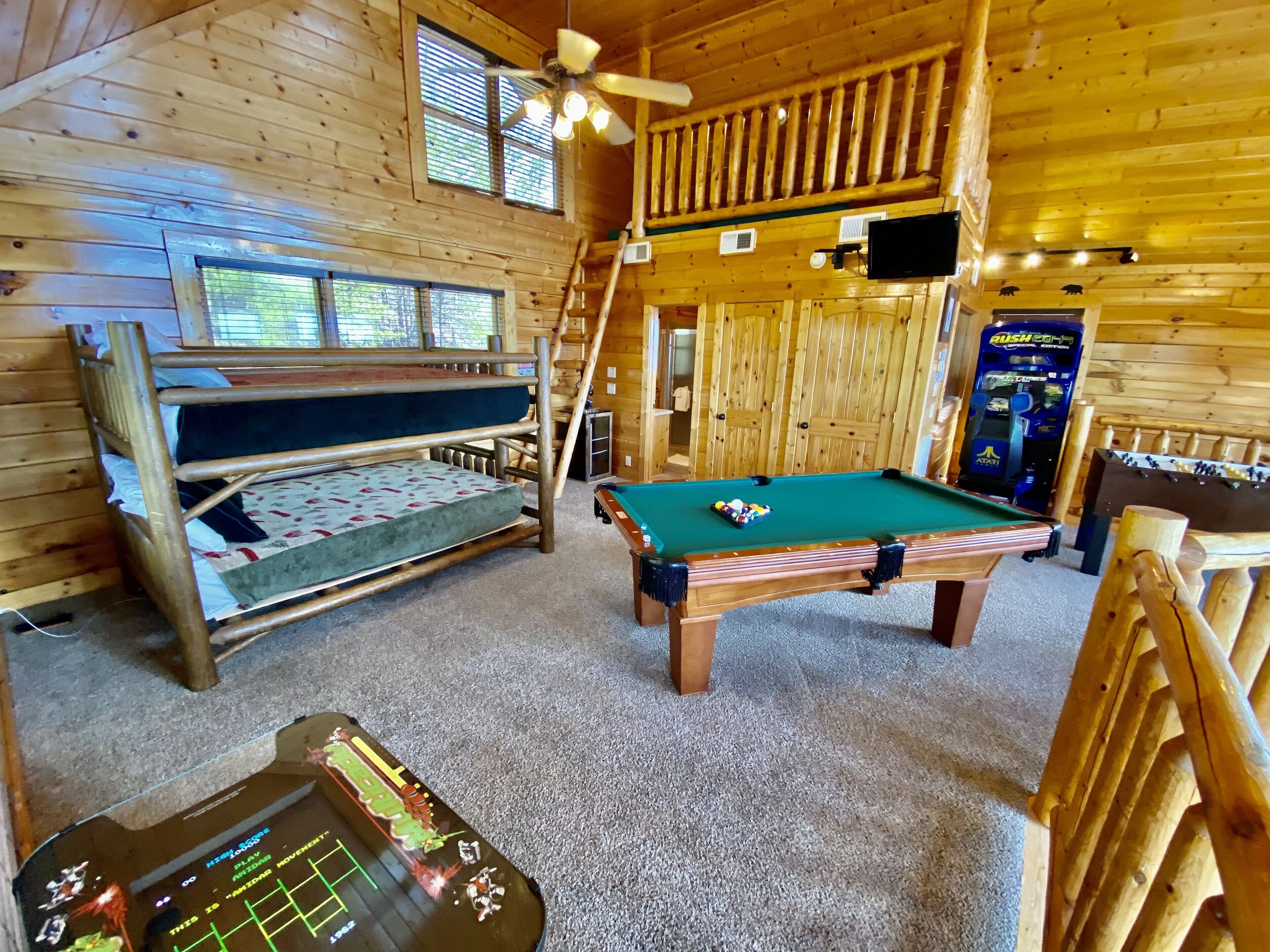 L’intérieur d’un chalet en bois, avec des lits superposés, une table de billard et une table de baby-foot.