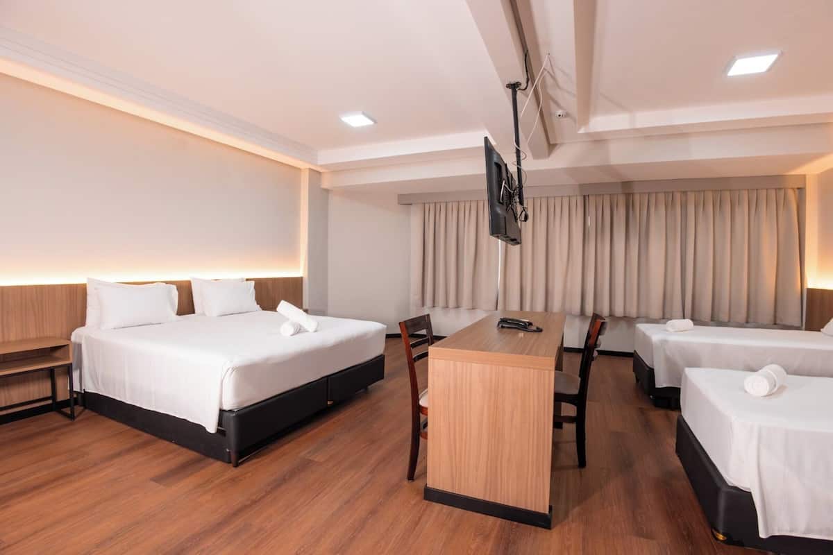 Una habitación de hotel con dos camas, un escritorio y una televisión.