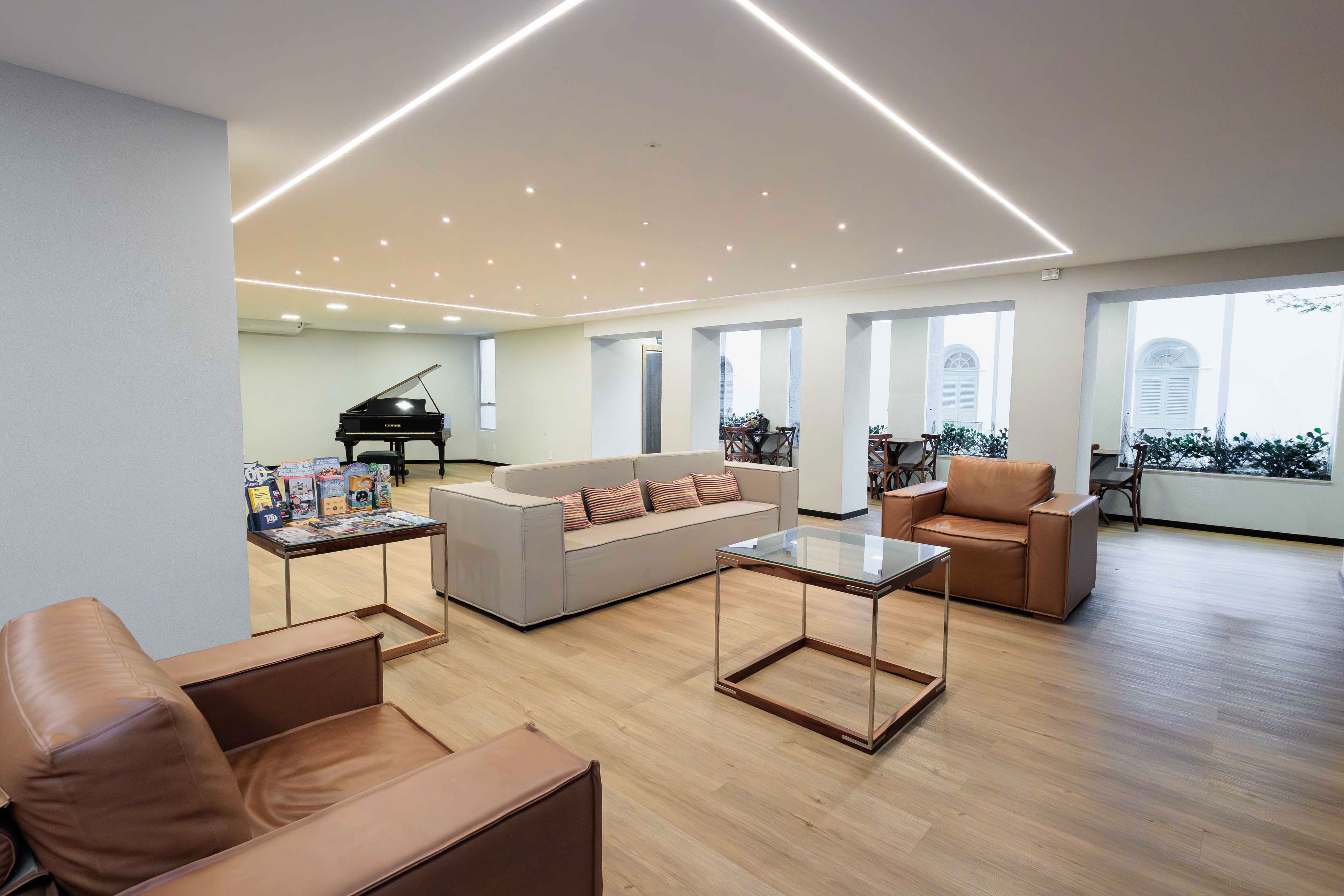 Un salón amplio con un piano, sofás de cuero y una mesa de centro de vidrio.