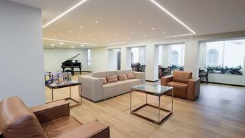 Un salón amplio con un piano, sofás de cuero y una mesa de centro de vidrio.