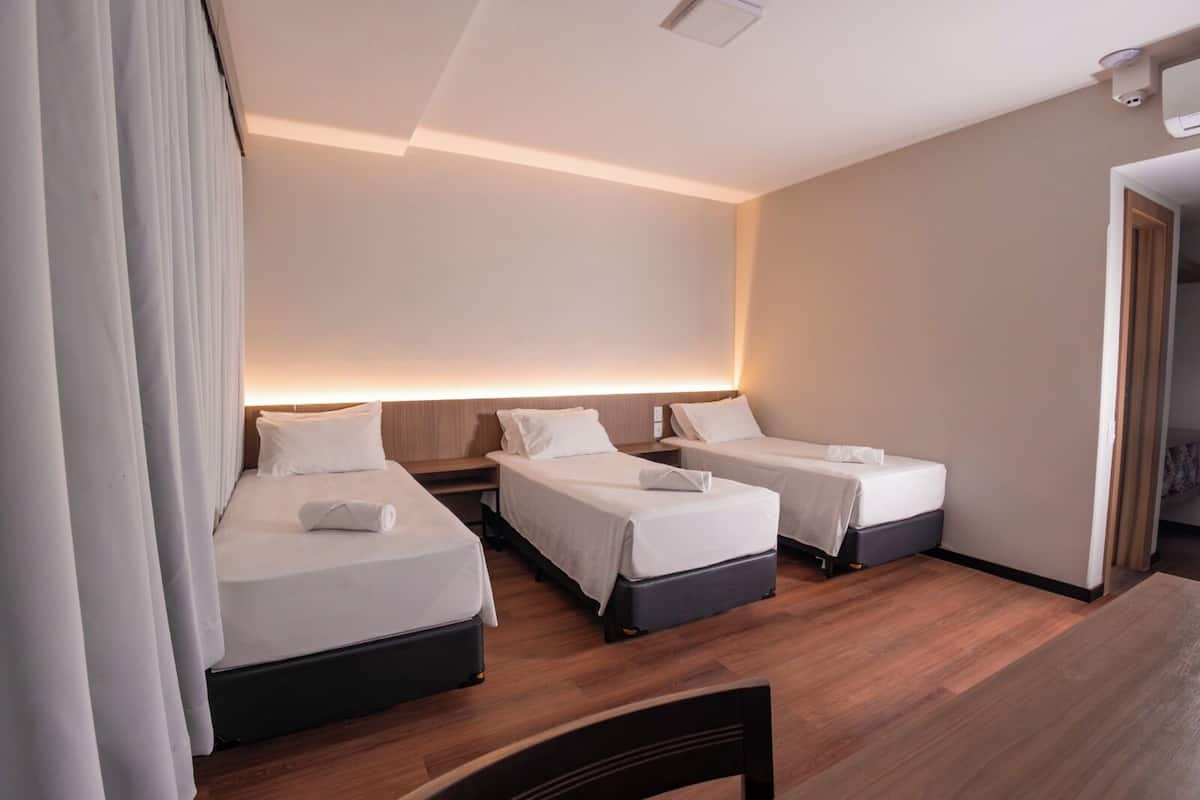 Habitación de hotel con dos camas, piso de madera y un ventanal grande.