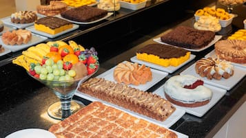 A buffet with various desserts and fruits.