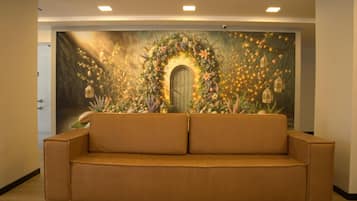 Una habitación con un amplio mural floral, un sofá marrón y una puerta de madera.