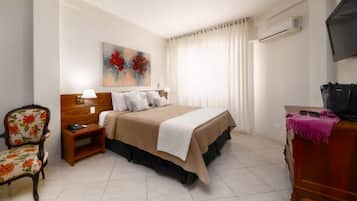 Una habitación de hotel con una cama, una silla, un escritorio y un televisor.