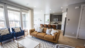 A modern living room with a blue sofa, a brown sofa, and a white coffee table. There is a patterned rug on the floor. - 5 Bedroom & 5 Bathrooms Beautiful Washington Home. YEAR ROUND Pool access (Washington)