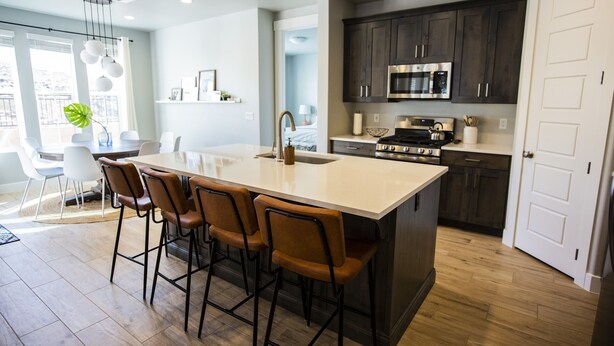 A modern kitchen with dark cabinets, a stainless steel microwave, and a large island with bar stools. - 5 Bedroom & 5 Bathrooms Beautiful Washington Home. YEAR ROUND Pool access (Washington)