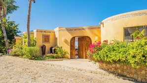 A building with a curved facade, a wooden door, and a stone pathway leading to it.