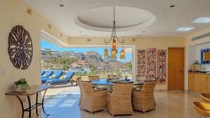 A dining area with wicker furniture, a view of the landscape, and a chandelier.