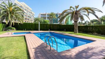 Relax by the pool surrounded by lush greenery and palm trees.