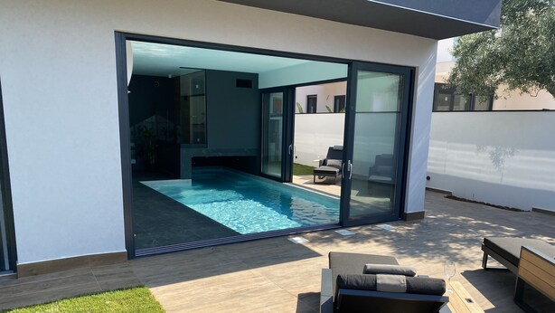 A modern outdoor pool area with a glass door leading to a patio. - LuxuriousVilla , sauna, sea view, 200 m from the beach (Fažana)