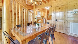 A wooden interior with a dining table, chairs, and a chandelier. - 'Mountain Dreams' Cabin: Hot Tub, Sauna & Views! (Sevierville)