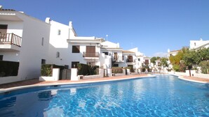 A swimming pool surrounded by white buildings with balconies. - CALETA townhouse 1st line to the sea, communal swimming pool (Miami Playa)