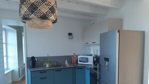 A modern kitchen with blue cabinets, a stainless steel refrigerator, a microwave, and a coffee maker.