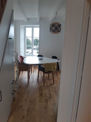 Een eetgedeelte met een ronde tafel, stoelen en een hanglamp.