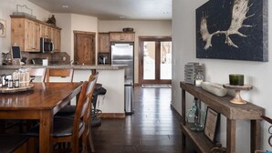 Une cuisine spacieuse avec des meubles de rangement en bois, un coin repas comprenant une table et des chaises en bois, et un couloir menant à une porte.
