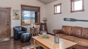 Un salon avec une table en bois, un canapé en cuir et une fenêtre donnant sur les montagnes.