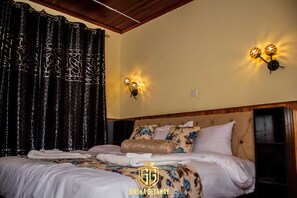 A hotel room with a neatly made bed, decorative curtains, wall sconces, and a wooden headboard. - Sirona Getaway Hotel (Nairobi)