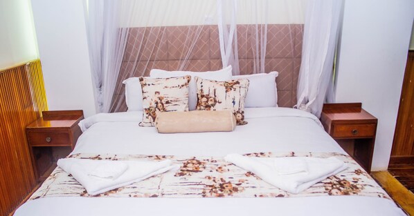 A neatly made bed with a floral bedspread, two pillows with a similar pattern, and a beige throw blanket. - Sirona Getaway Hotel (Nairobi)