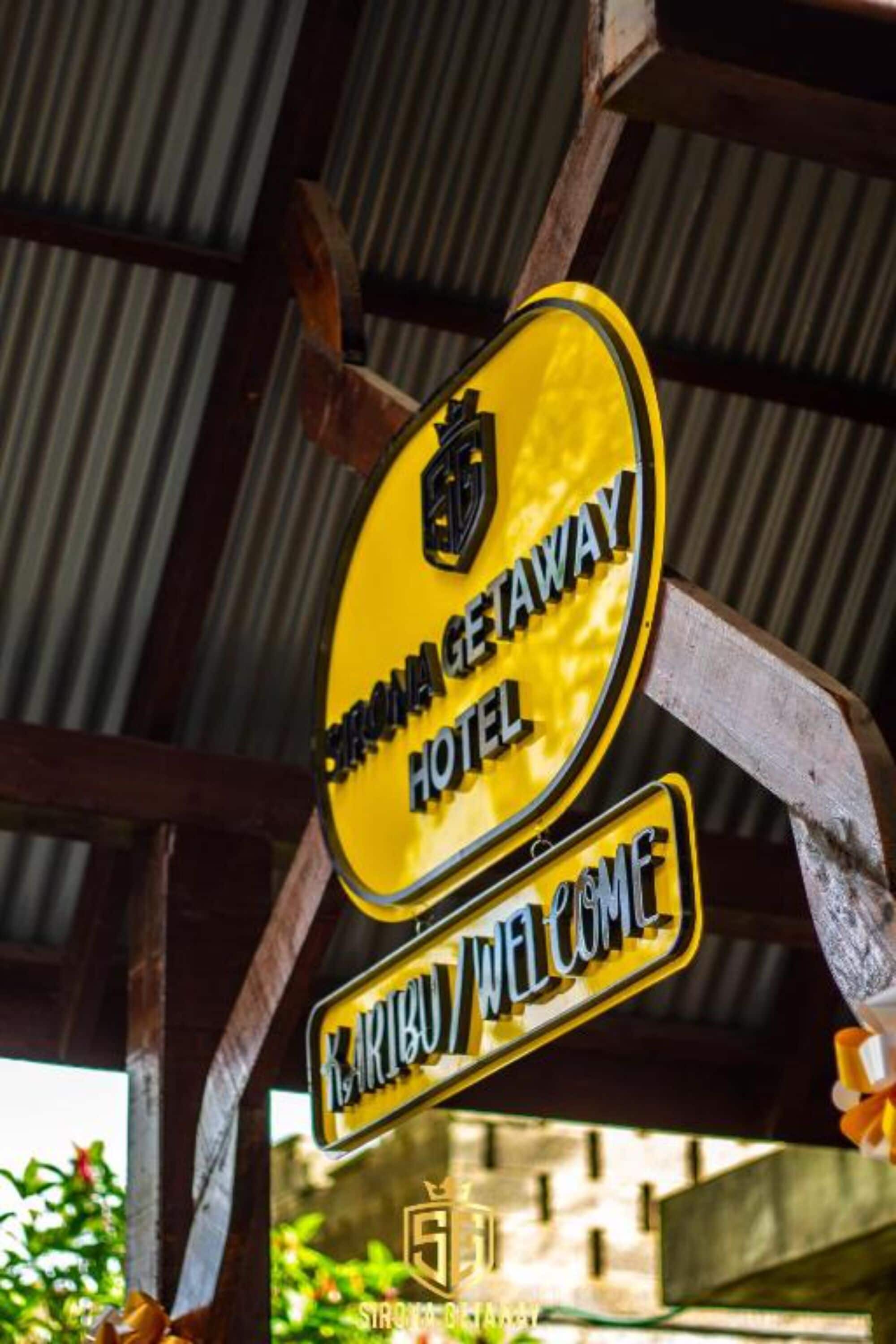 A yellow sign with the text 'STRONG GETAWAY HOTEL' and 'KARIBU WELCOME' on a metal structure.