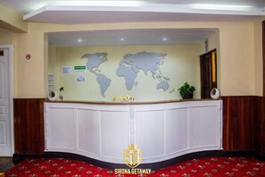 A reception desk with a world map, a sign for "Sirona Getaway," and a potted plant.