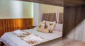 A hotel room with a bed, a wooden headboard, and a canopy bed.