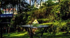 A round table with a floral centerpiece in an outdoor garden setting. - Sirona Getaway Hotel (Nairobi)
