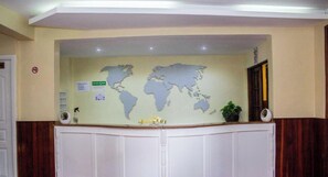 A reception desk with a world map, a sign for "Sirona Getaway," and a potted plant. - Sirona Getaway Hotel (Nairobi)