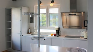 Una cucina moderna con frigorifero integrato, cappa in acciaio inox e una finestra che permette l'illuminazione naturale.
