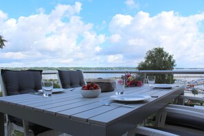 Een eettafel gedekt met een fruitschaal, borden en bestek, met uitzicht op een jachthaven met boten.