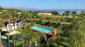 A pool surrounded by lush greenery, a clear blue sky, and a distant view of the sea and mountains. - Villa Solemare Verde Privat Pool. (Balestrate, Sizilien)