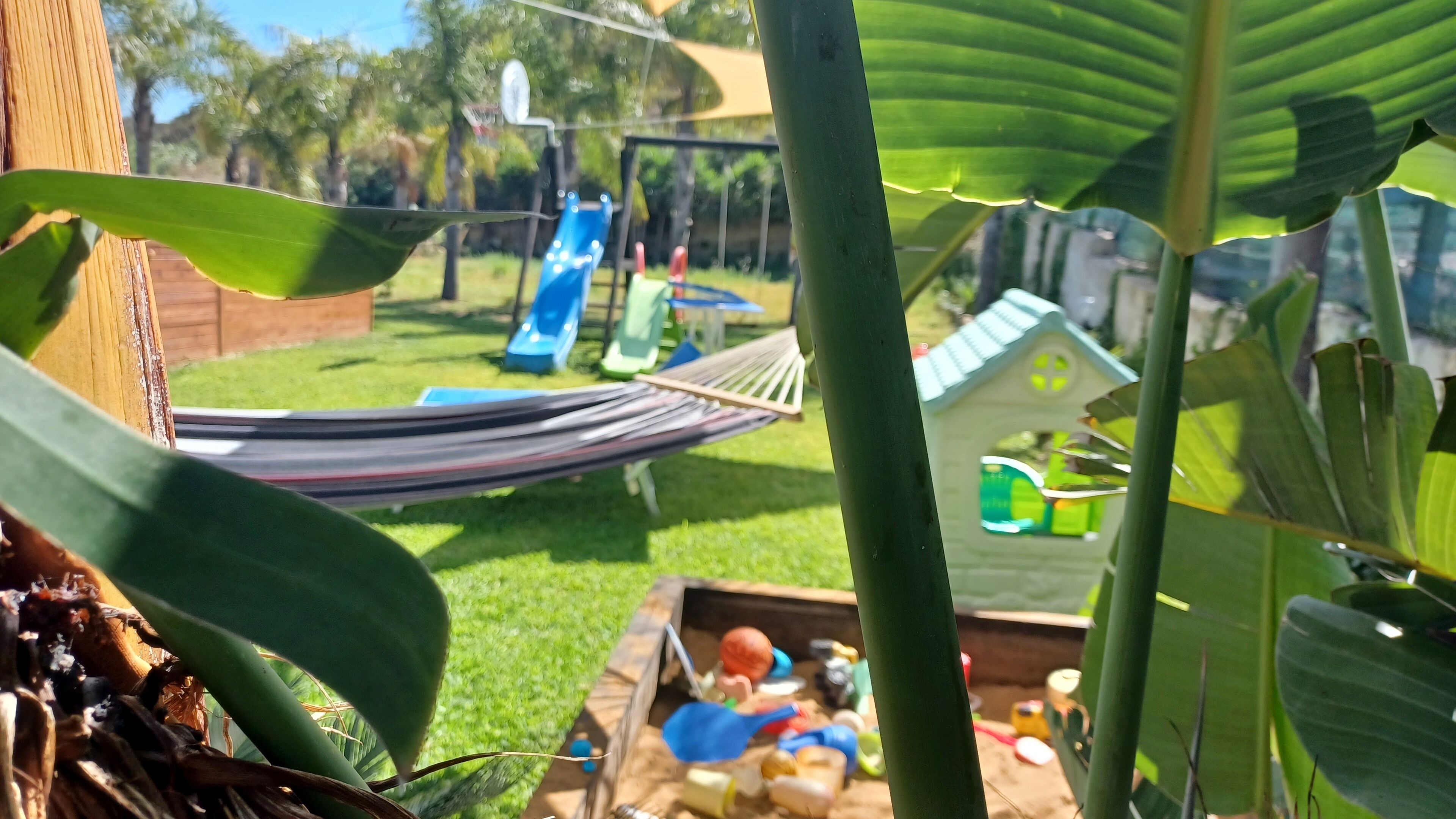 A hammock, a small playhouse, and a slide in a backyard.