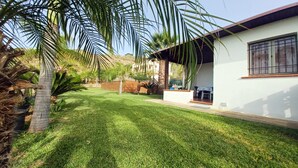 A well-maintained lawn with palm trees, a patio area, and a building with barred windows. - Villa Solemare Verde Privat Pool. (Balestrate, Sizilien)