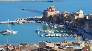 A coastal town with a historic castle, a marina with boats, and a mix of traditional and modern buildings. - Villa Solemare Verde Privat Pool. (Balestrate, Sizilien)