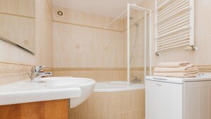 Un baño moderno con lavamanos, bañera y lavadora blanca.