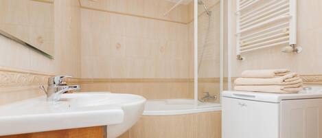 A modern bathroom with a sink, bathtub, and a white washing machine.
