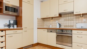 Una cocina moderna con armarios color beige, un microondas, una cafetera, un hervidor y un horno.