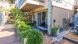Un immeuble résidentiel doté d’une terrasse en bois, d’un banc et de plantes en pot.