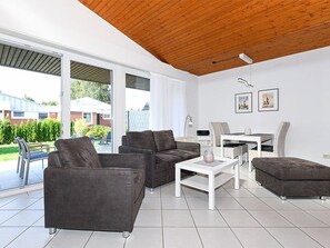 Una sala de estar moderna con techo de madera, un comedor y vistas al exterior.