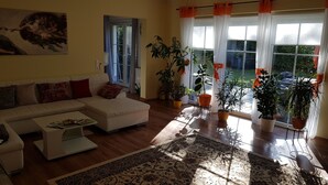 A living room with a sofa, coffee table, and potted plants. - Holiday house Fichtenwalde, 160m², 2.5 BZ, 3SZ, WZ, dining room, kitchen, garden, VDSL (Beelitz)