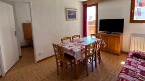 Un comedor con una mesa y sillas, un televisor y un ventanal con vistas.