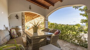 Eine Terrasse mit Korbmöbeln, einer Steinmauer und Blick auf die Landschaft.