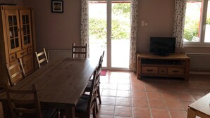 A dining area with a wooden table and chairs, a television on a wooden stand, and a cabinet with glass doors. - Le Petit Paradis Provençal (Cigales 2) (Allemagne en Provence)
